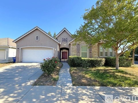 A house with a driveway and a tree in front.