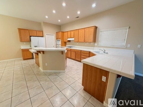 A kitchen with white appliances and wooden cabinets is available for rent.