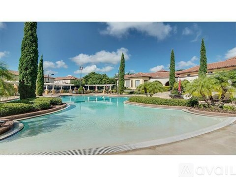 A large pool surrounded by trees and bushes with a building in the background.