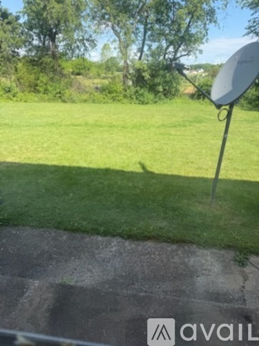 A satellite dish is mounted on a pole in a grassy area.