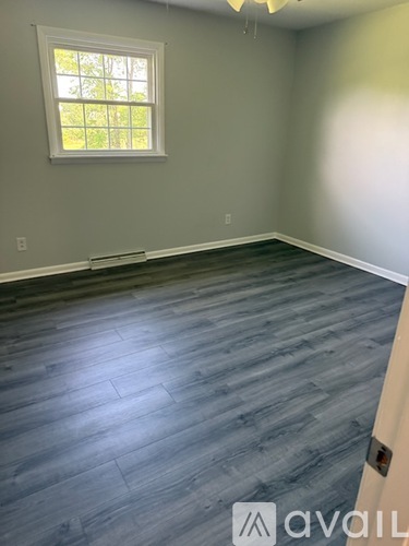 A room with a window and wooden flooring.