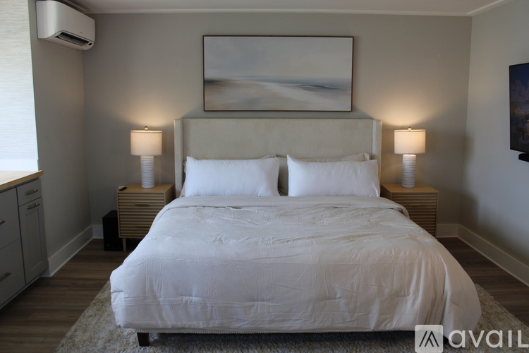 A bedroom with a large bed and two lamps.