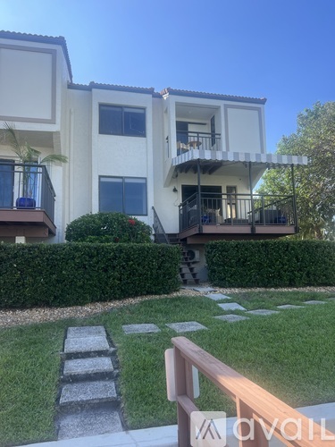 A white building with a balcony and a garden in front.