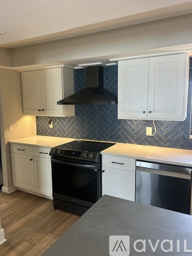 A kitchen with white cabinets and a black hood.