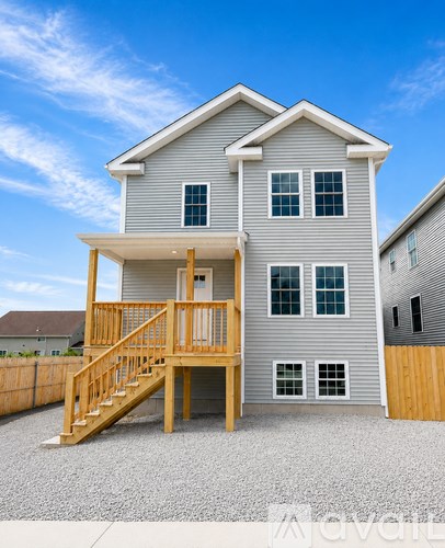 A two-story house with a wooden deck and stairs.