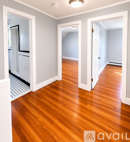 A hallway with wood floors and white walls.