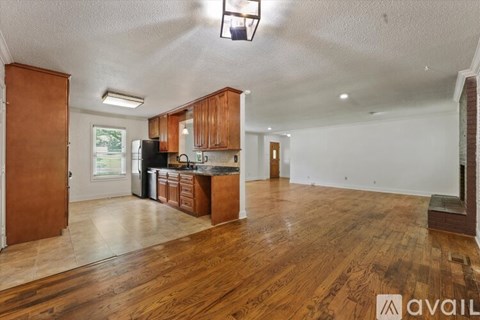 A kitchen with wooden cabinets and a black fridge is available for rent.