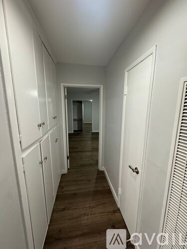 A long hallway with white doors and wooden floors.