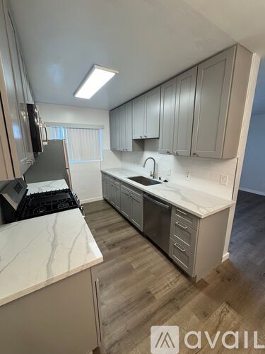 A kitchen with a white countertop and grey cabinets.