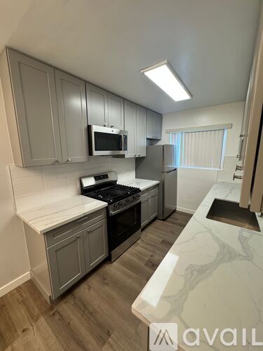 A kitchen with a marble countertop and wooden flooring.