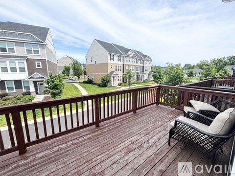 A wooden deck with a chair and a railing in front of apartment buildings.