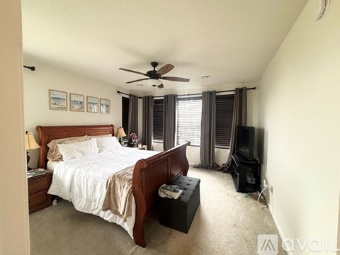 A bedroom with a bed, nightstand, and window with curtains.