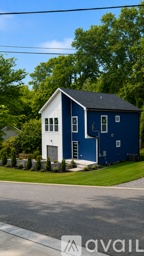 A blue house with white trim is situated on a street with a green lawn.