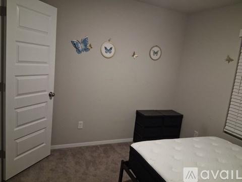 A bedroom with a white bed, a black dresser, and three wall decorations.