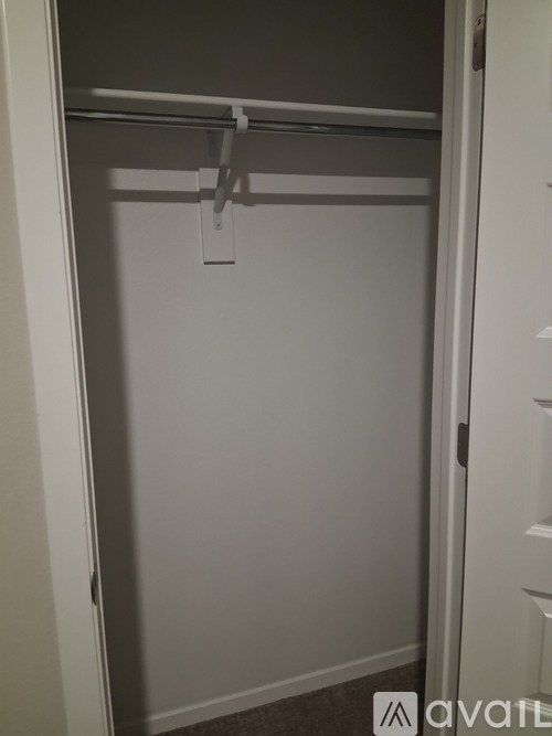 A white closet with a hanger on the rod.