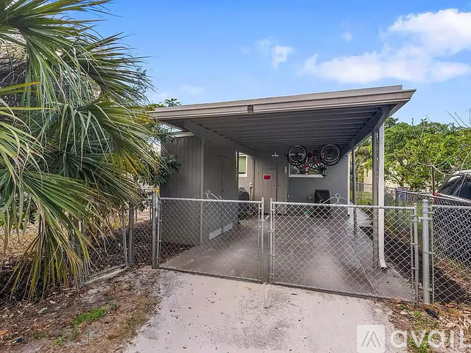 A small building with a metal roof and a gate in front of it.
