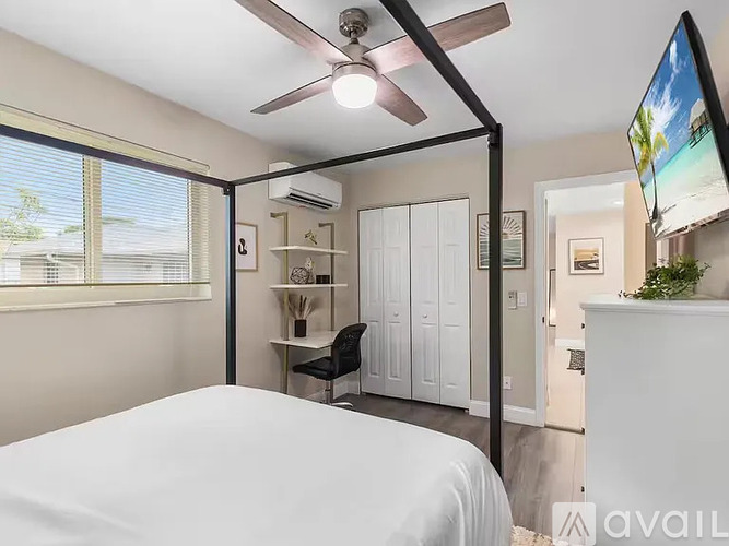 A bedroom with a bed, a ceiling fan, and a television.
