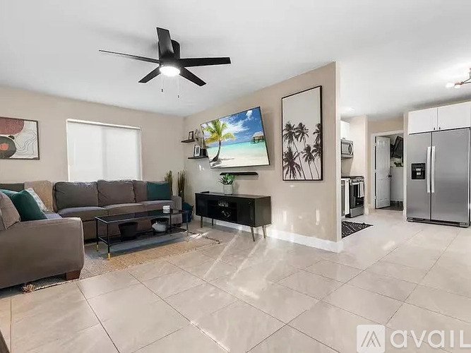 A living room with a brown couch and a flat screen TV mounted on the wall.