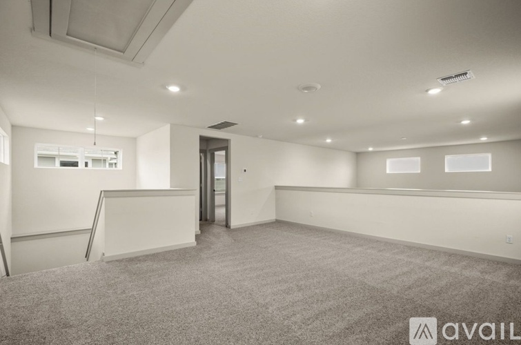 A spacious room with a carpeted floor and a door in the background.