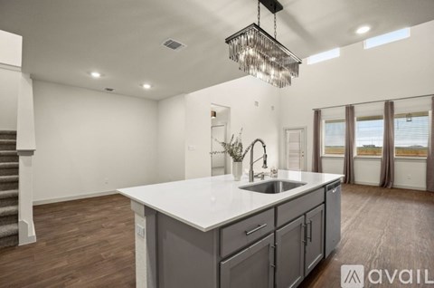 A modern kitchen with a large island and a chandelier hanging from the ceiling.