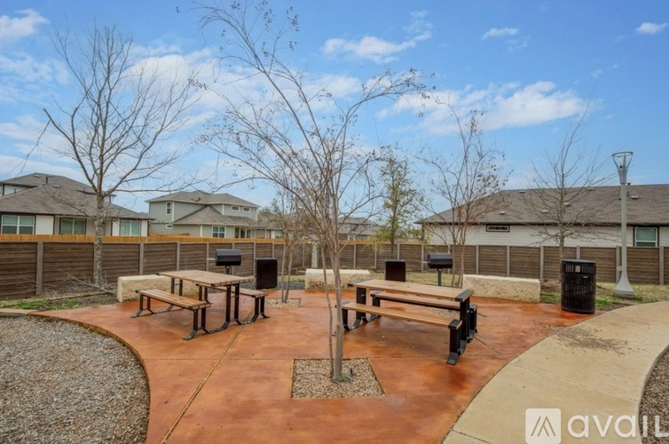 A park area with benches and trees in front of apartment buildings.