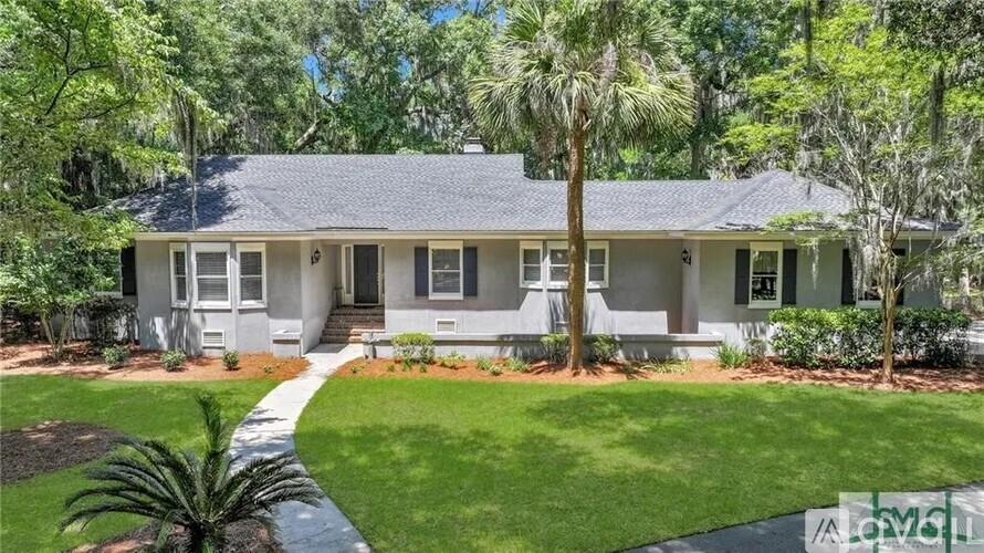 A house with a well-maintained lawn and trees in the background.