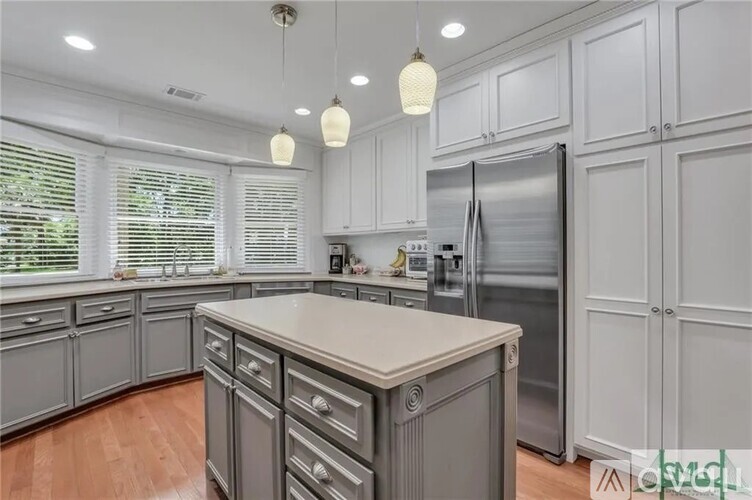 A kitchen with a refrigerator, cabinets, and a countertop.