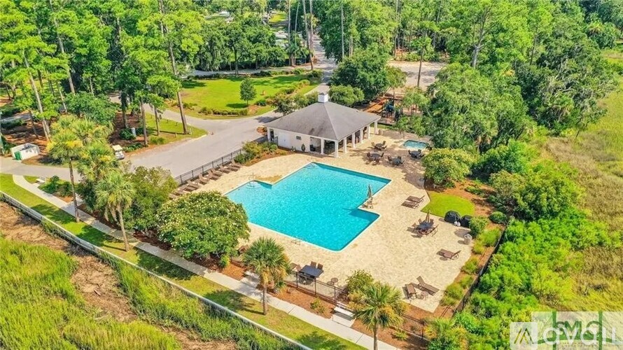 A large swimming pool surrounded by a sandy area and a pavilion.