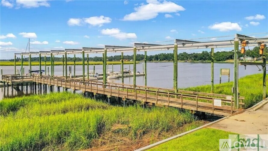 A wooden bridge over a body of water with a green grassy area on the left.