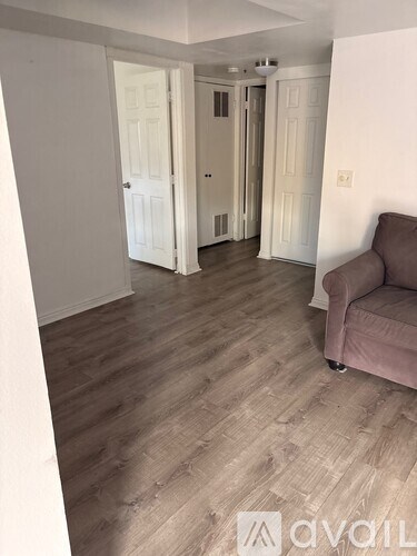 A living room with a brown sofa and wooden flooring.