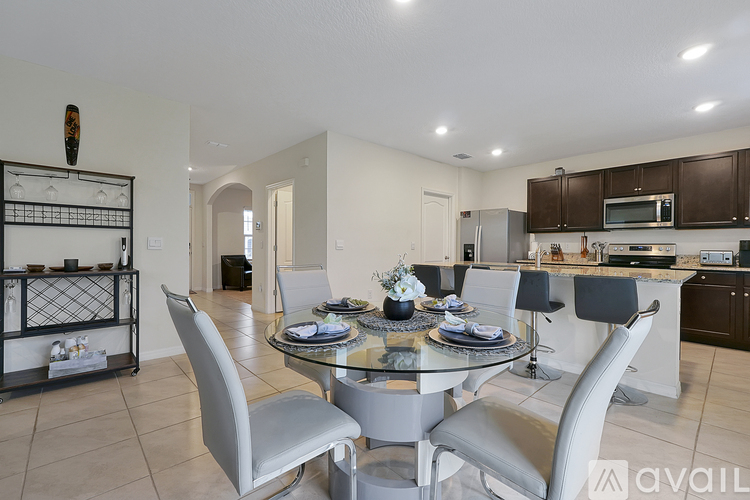 A modern dining room with a glass table and grey chairs.