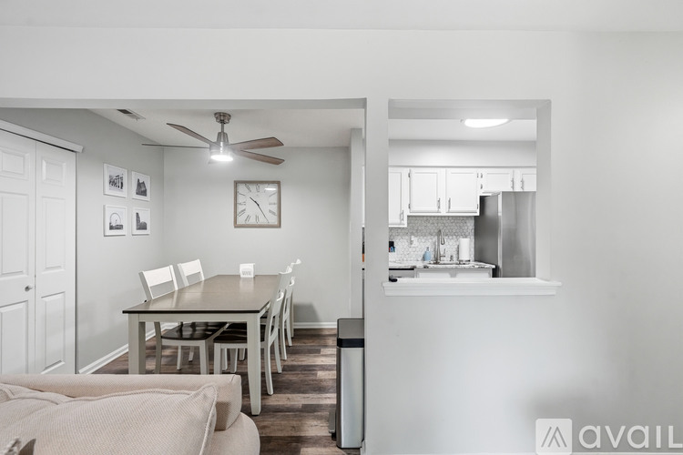 A kitchen with a table and chairs in the foreground and a fridge in the background.