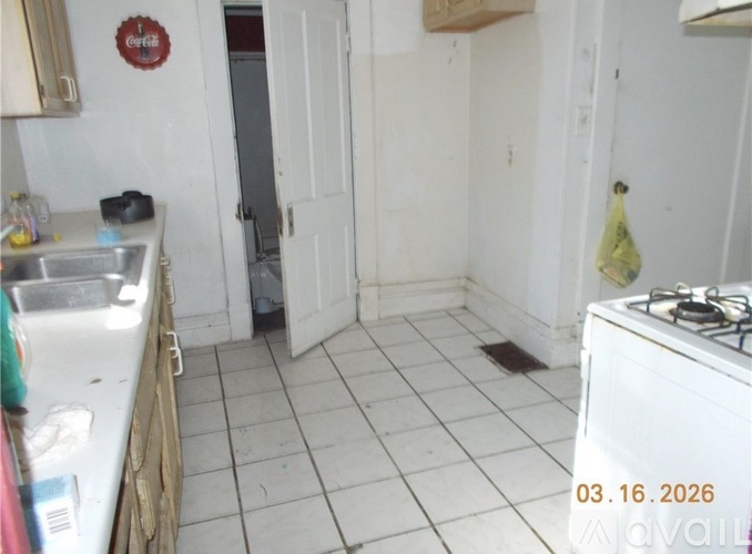 A kitchen with a white stove and a white tiled floor.