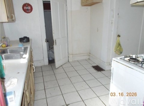 A kitchen with a white stove and a white tiled floor.