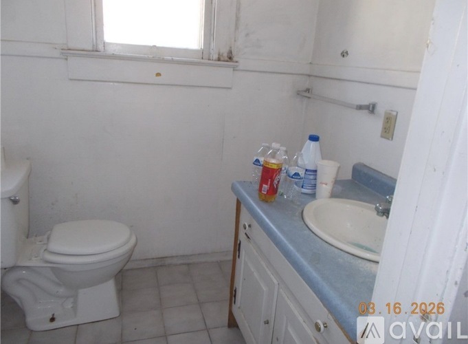 A bathroom with a toilet, sink, and a window.