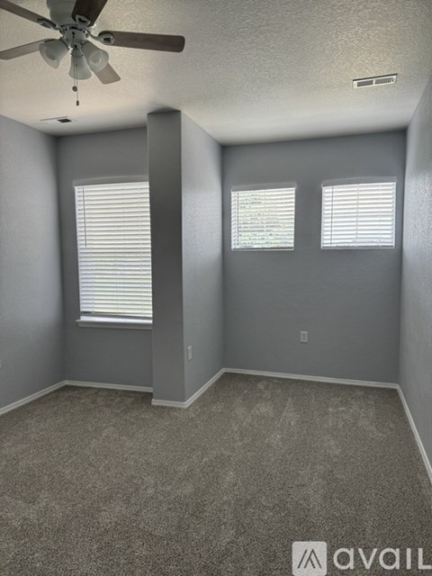 A room with a ceiling fan and carpeted floor.