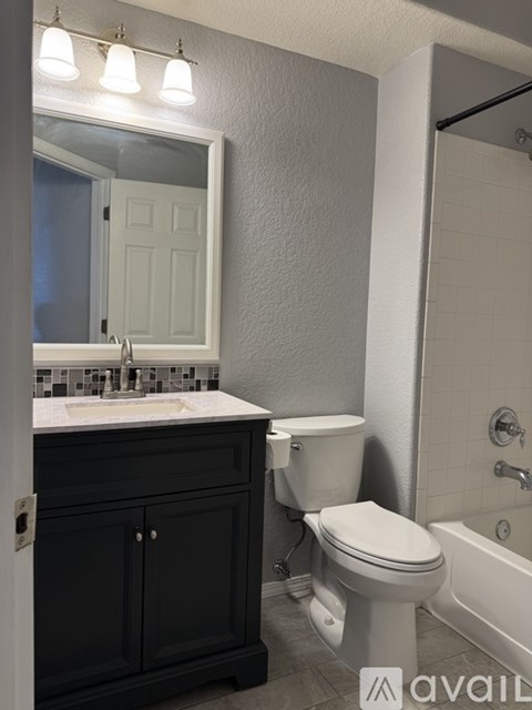 A bathroom with a white toilet and a black cabinet.
