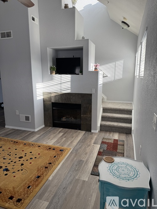 A living room with a fireplace and a rug on the floor.