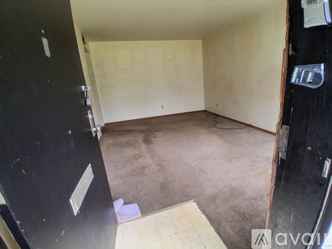 A room with a black door and walls with a wooden floor.
