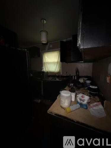 A kitchen with a table full of food containers and a refrigerator.