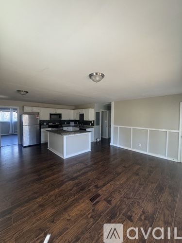 A kitchen with white cabinets and a wooden floor.