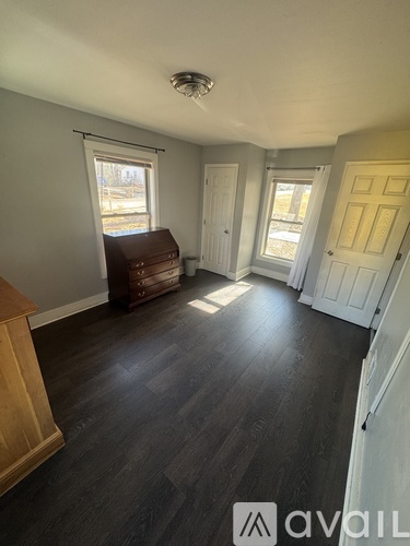 A room with a brown couch and a wooden cabinet.