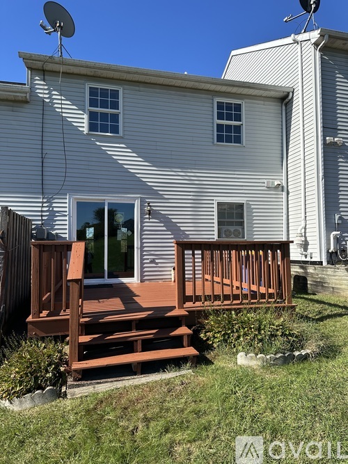A house with a wooden deck and a satellite dish on the roof.