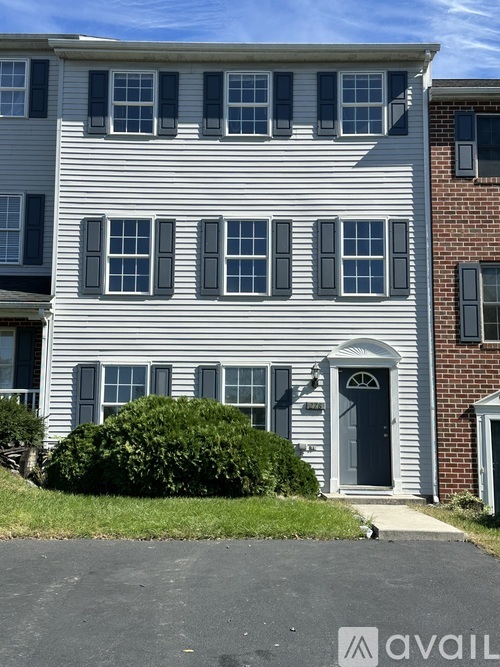 A two-story building with a grey facade and a black door.