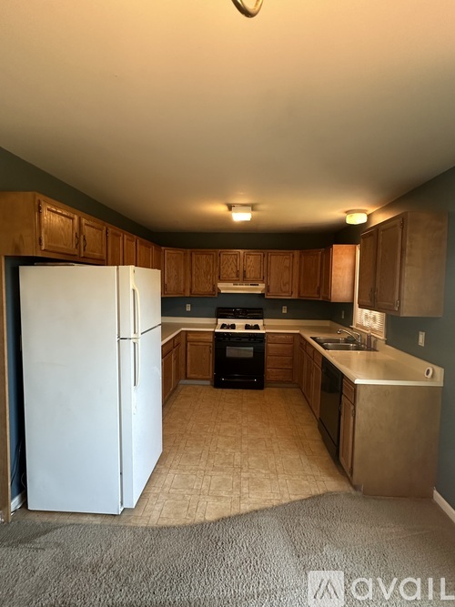 A kitchen with a white refrigerator and wooden cabinets.