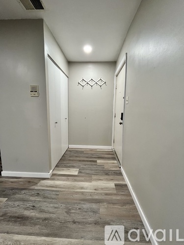 A hallway with a wooden floor and white walls.