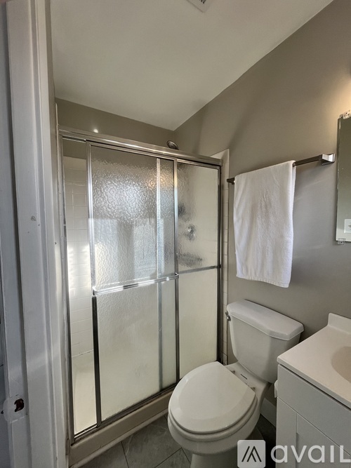 A white toilet sits next to a walk-in shower with a glass door.