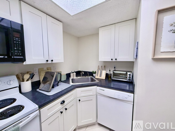 A kitchen with white cabinets and black appliances.