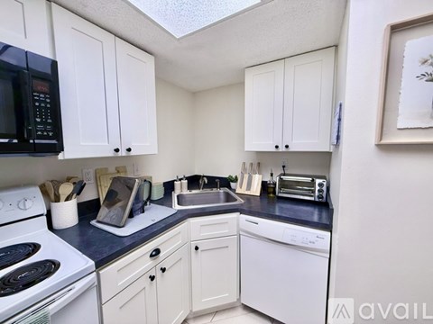 A kitchen with white cabinets and black appliances.