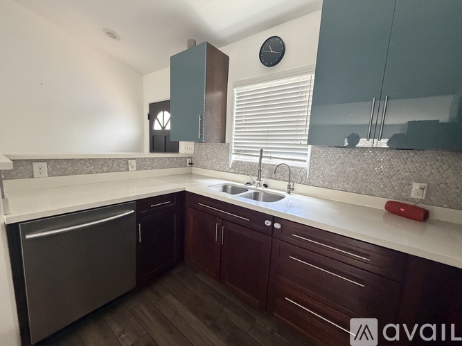 A kitchen with dark wood cabinets and a stainless steel dishwasher.